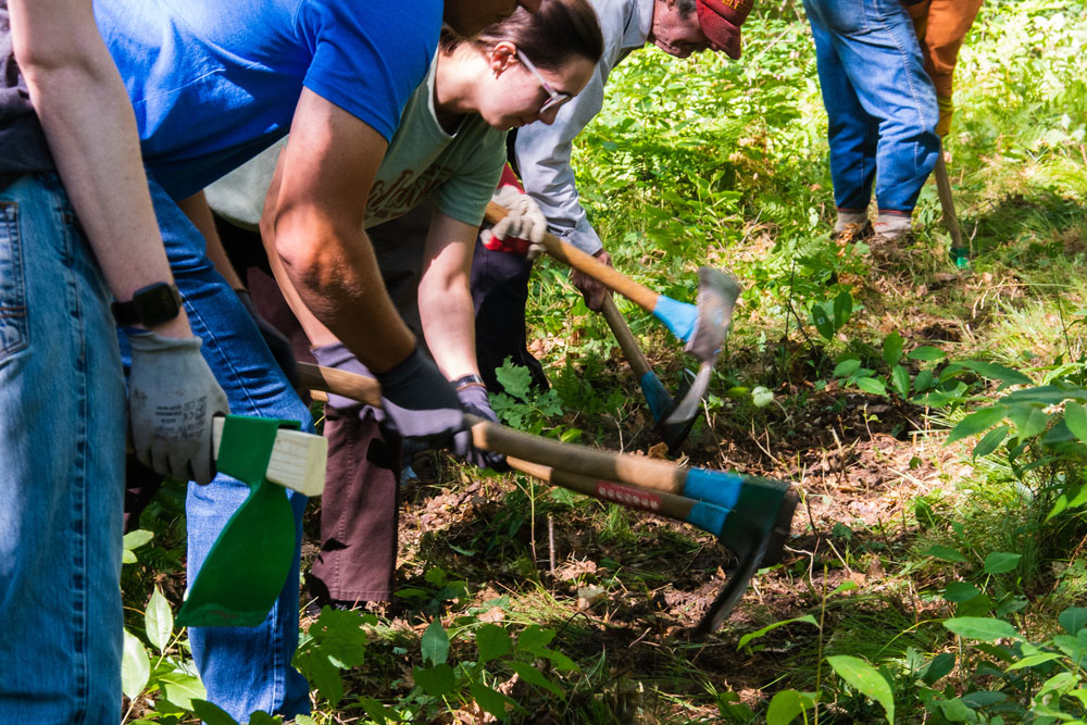 Volunteers wield tools to build trail at Upriver Nature Preserve.